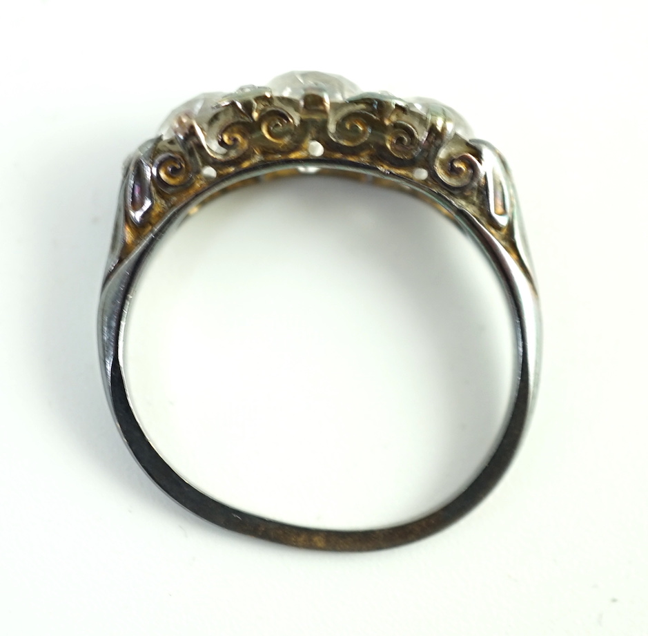 An antique gold, silver and graduated three stone diamond set ring, with diamond chip spacers and diamond chip set shoulders